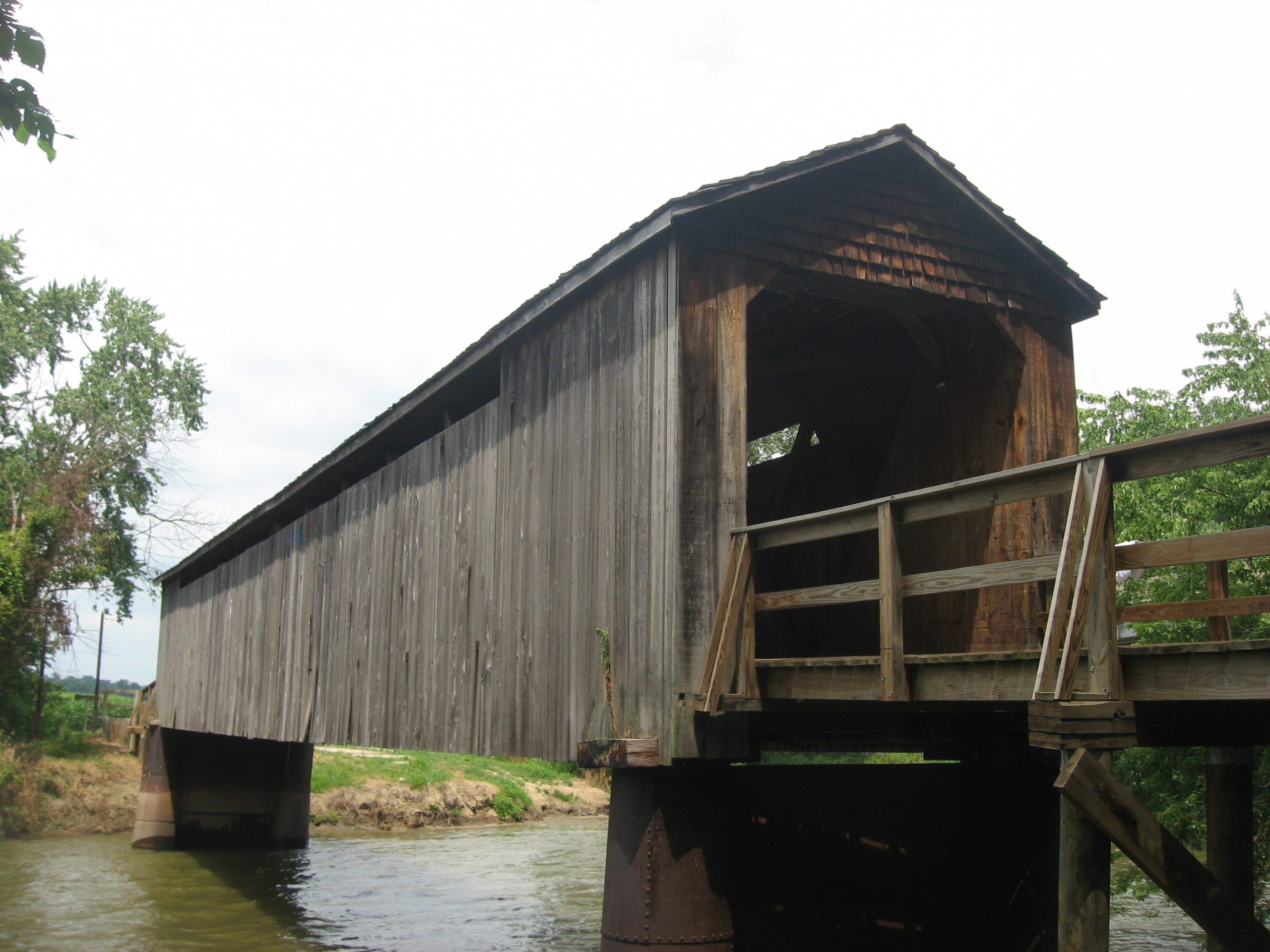Southern portal and western side of the Thompson Mill Covered Bridge , which carries the old roadbed of County Road 1700E over the Kaskaskia River northeast of Cowden in Shelby County , Illinois , United States